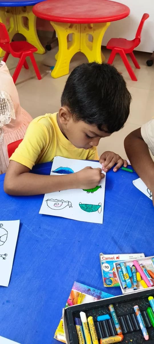 Toddler drawing colorful strokes on paper using chunky crayons