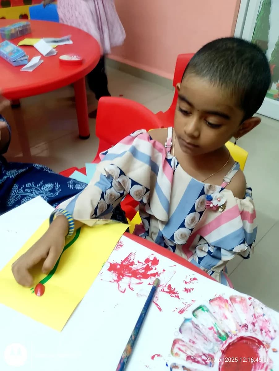 Child using painted seashells to create a blooming flower design on paper