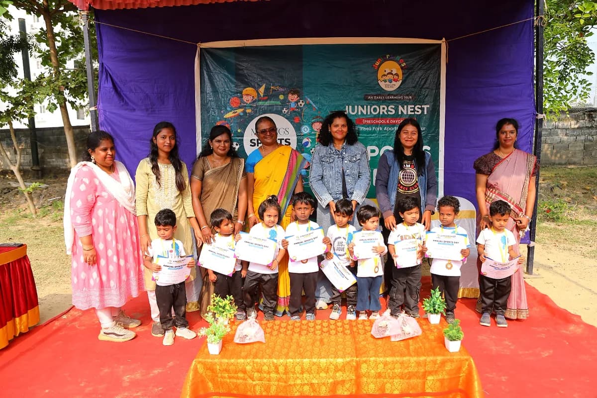 Teachers and students on stage holding Sports Day achievement certificates and medals